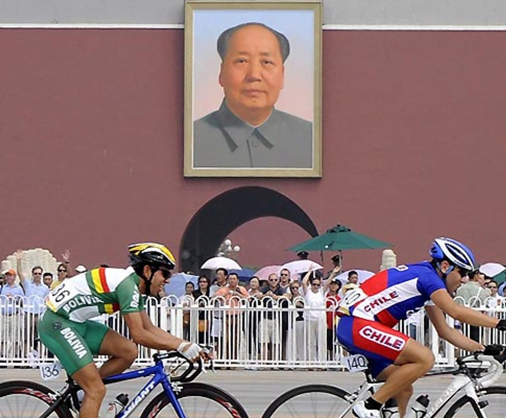 Ciclistas pedalam sob o olhar de Mao (Foto EPA)