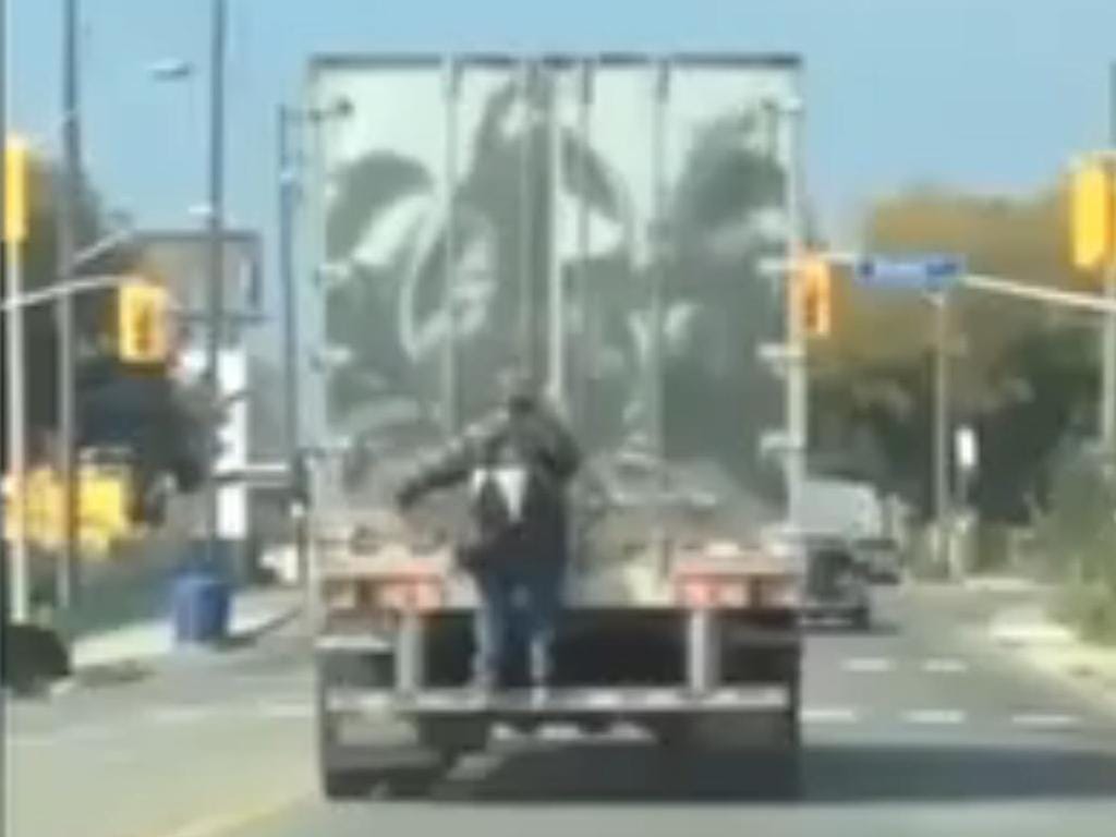 Homem pendurado à boleia em camião TIR (Reprodução Telegraph)