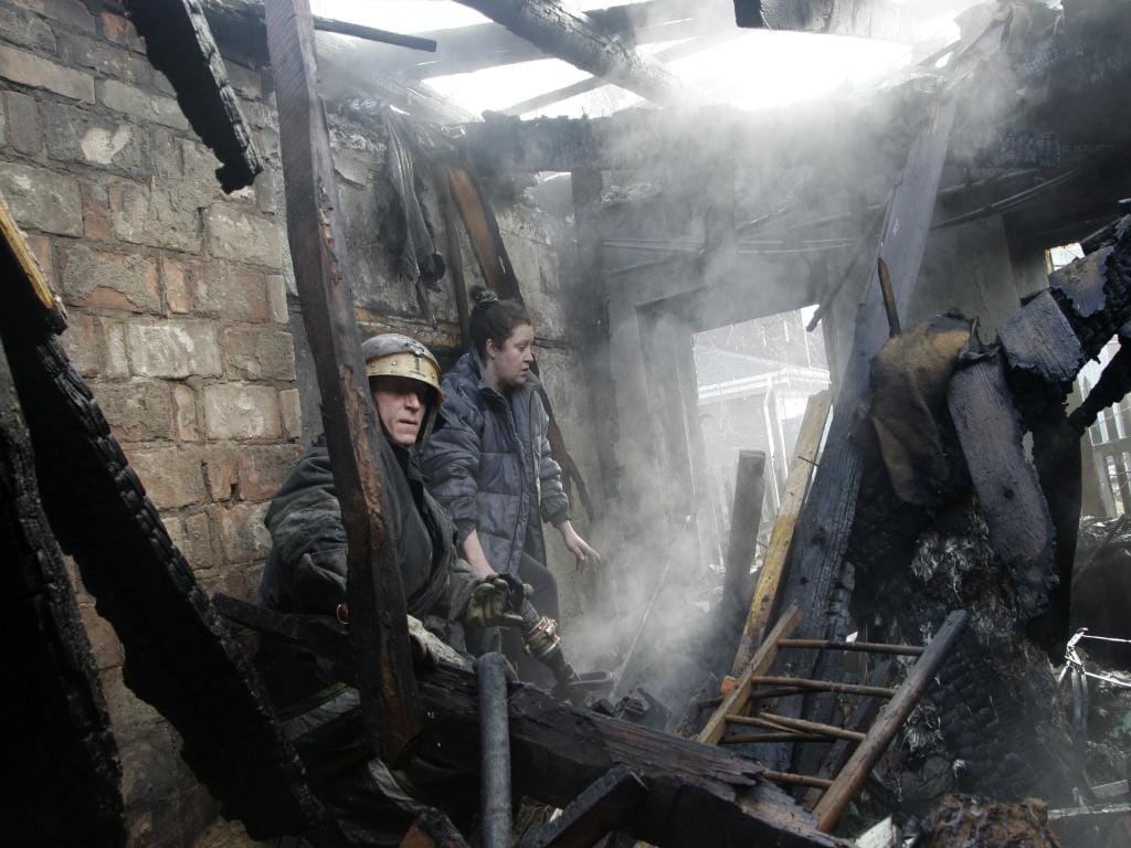 Mulher e bombeiro no meio dos escombros de uma casa (Reuters)