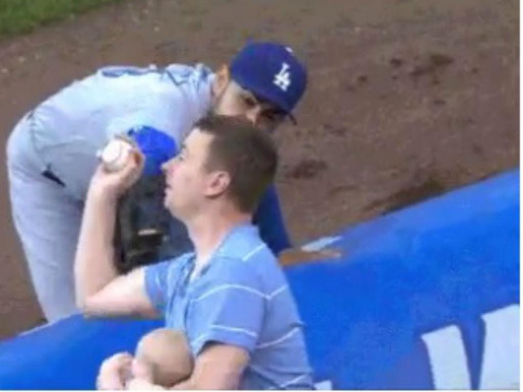 Pai agarrou bola perdida enquanto dava biberão ao filho num jogo de baseball [Twitter]