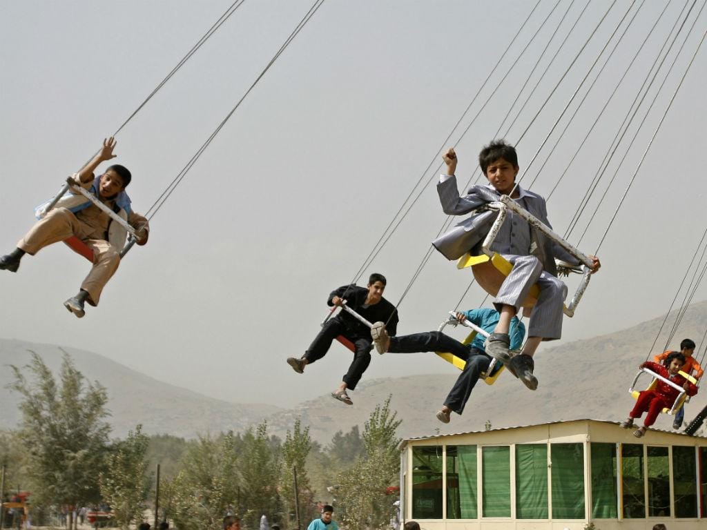 Crianças dão uma volta num carrossel suspenso no ar [Fonte: REUTERS/Omar Sobhani]