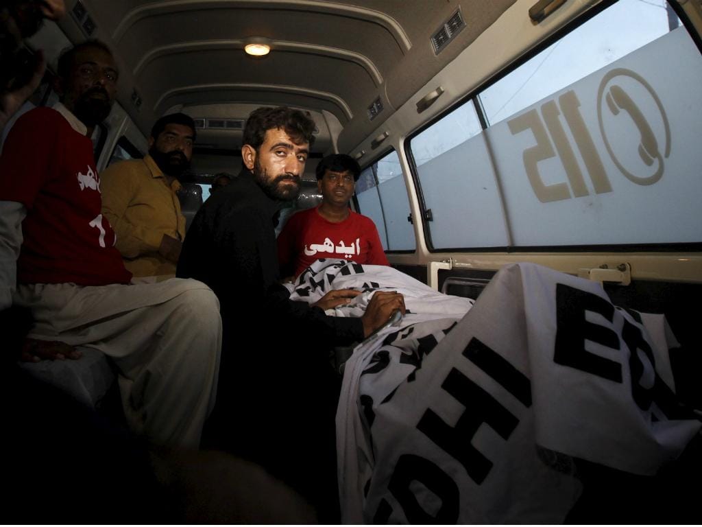 Abdul Majeed, irmão de Shafqat Hussain, ao lado do corpo de Shafqat depois deste ter sido executado [Reuters]
