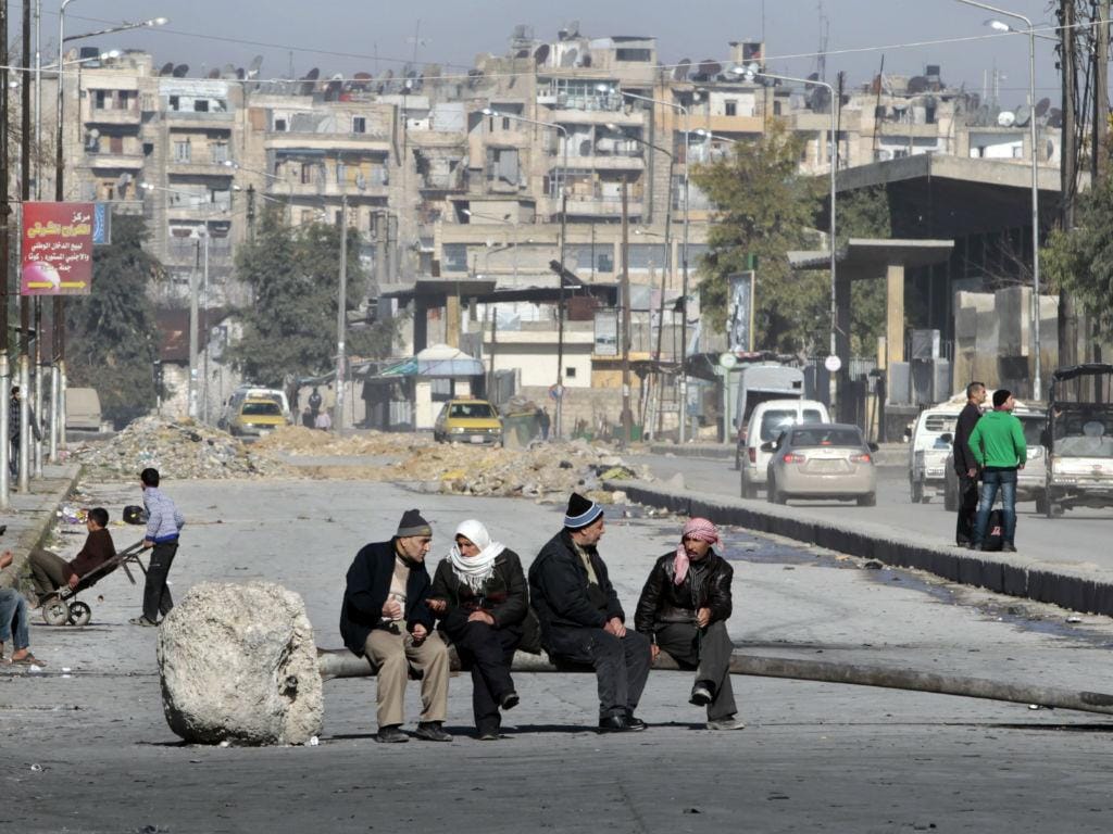 Homens sentados num destroço a guerra (REUTERS / Ahmed Jadallah)
