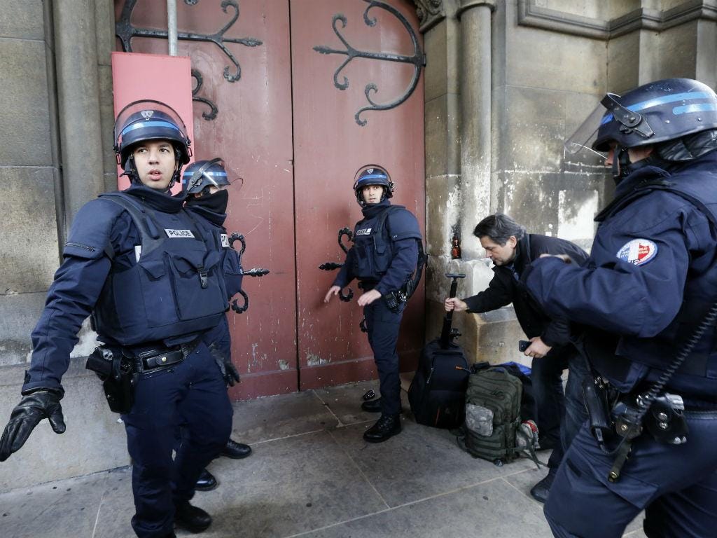 Polícia concentrada em frente à porta de uma igreja em Saint Denis, Paris, durante a caça aos jihadistas alegadamente responsáveis pelos atentados [Reuters]