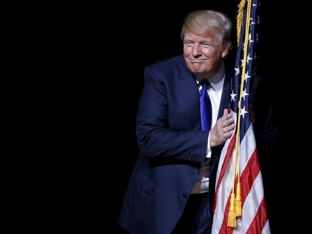 Candidato à nomeação republicana Donald Trump abraça uma bandeira dos EUA antes de uma reunião na sede de campanha em Derry, New Hampshire, 19 agosto 2015