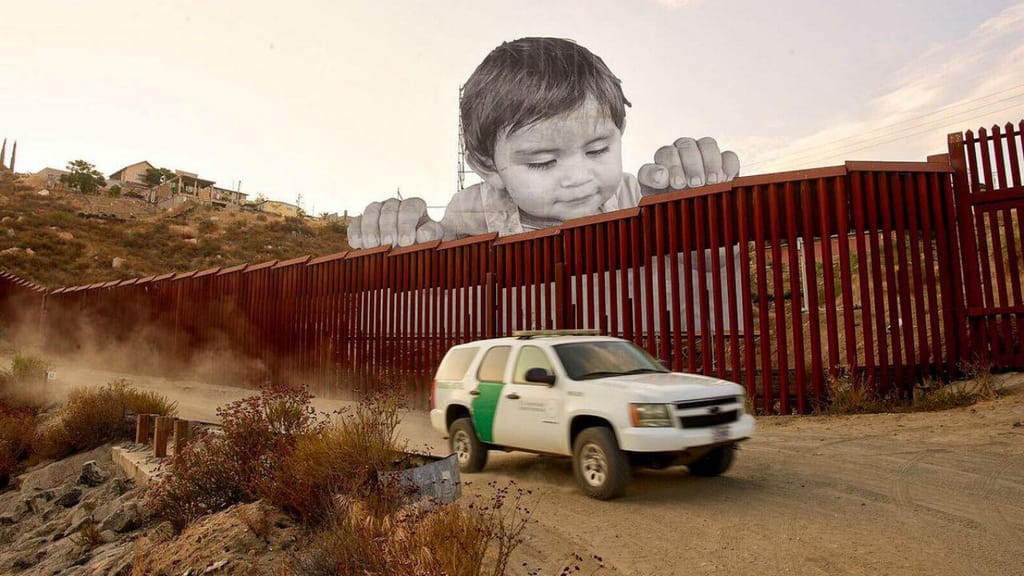 Criança a olhar para a fronteira entre o México e Estados Unidos 