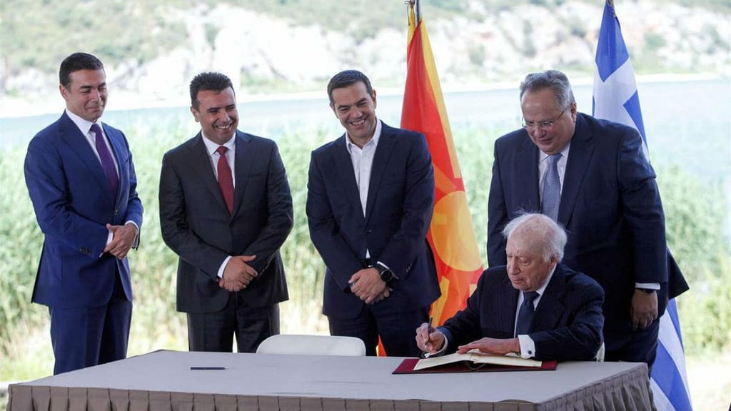 Alexis Tsipras, MNE grego, Nikos Kotzias e primeiro-ministro da Macedonia Zoran Zaev assinam acordo sob o olhar do enviado especial da ONU Matthew Nimetz