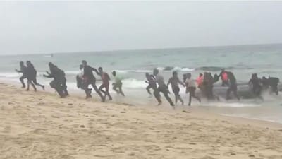 Migrantes desembarcam em praia espanhola enquanto turistas filmam e tiram fotografias - TVI