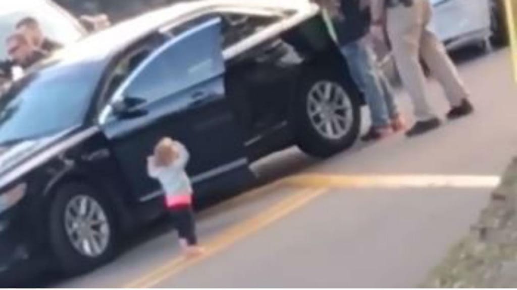 Bebé de braços no ar, depois de ver o pai ser preso pela polícia