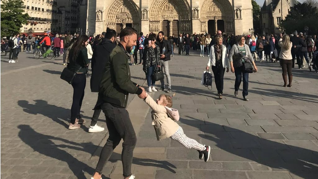Homem e criança a brincarem em frente à Catedral de Notre-Dame