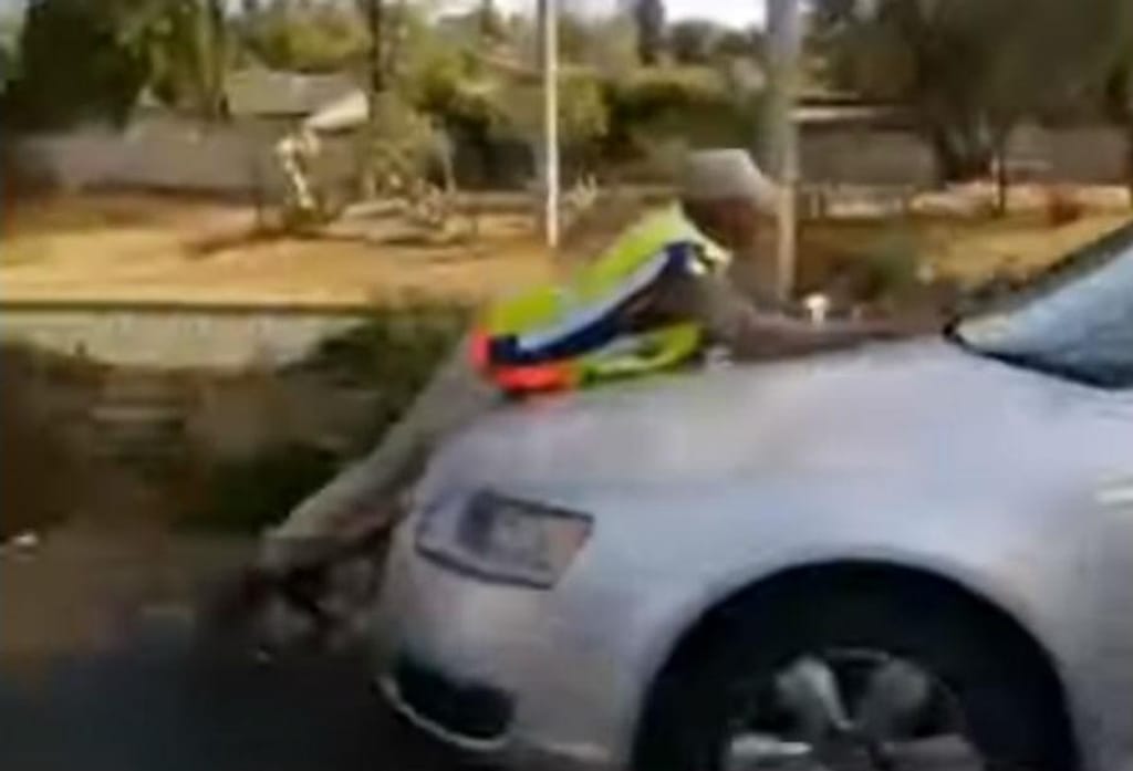 Polícia em cima do capô de um carro (reprodução YouTube)