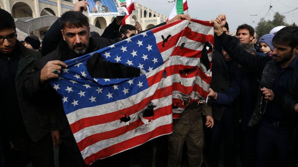 Manifestantes seguram bandeira dos Estados Unidos vandalizada em Bagdade