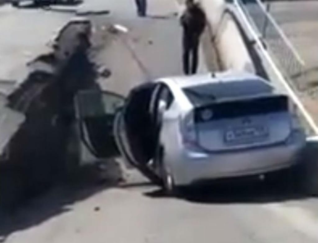 Carro cai em buraco que se abre na estrada (reprodução YouTube)