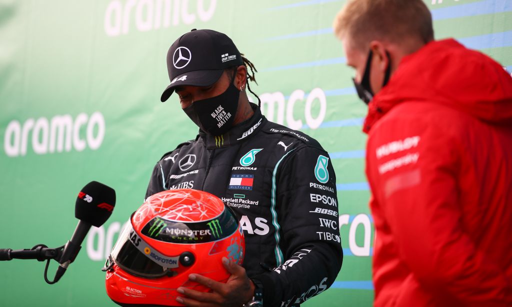 Lewis Hamilton recebe capacete de Michael Schumacher, das mãos de Mick Schumacher, após igualar as 91 vitórias do antigo corredor alemão (Bryn Lennon/AP)