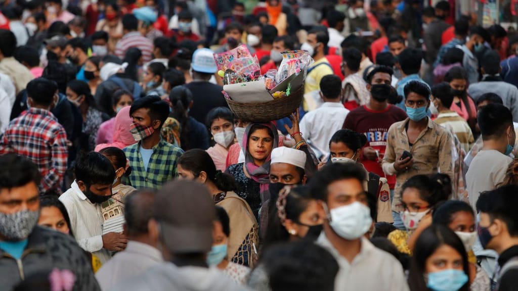 Covid-19: mulher caminha sem máscara num mercado apinhado na Índia