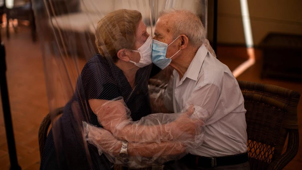 Agustina Cañamero, 81, e Pascual Pérez, 84, dão um beijo e um abraço através de uma película de plástico para evitar contrair o novo coranívurs num lar em Barcelona, em junho de 2020.