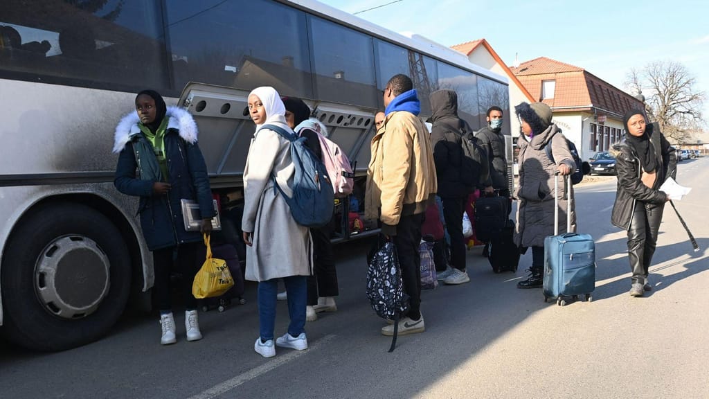 Estudantes universitários, incluindo muitos nigerianos, em fuga da capital ucraniana, Kiev, arrumam as suas malas no autocarro, perto da fronteira entre a Hungria e a Ucrânia, na vila húngara de Tarpa, a 28 de fevereiro de 2022. Foto: Attila Kisbenedek/AFP/Getty