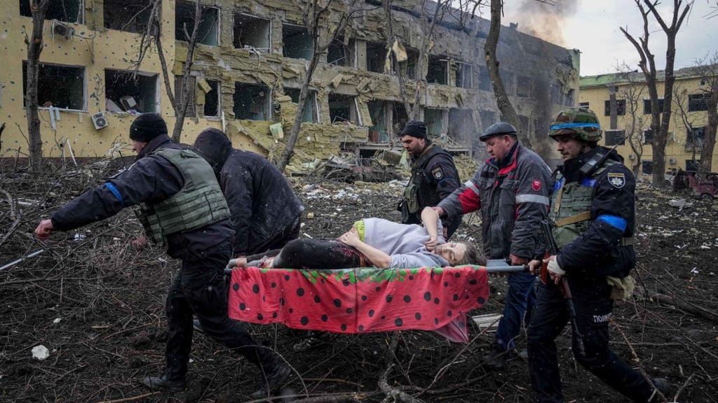 Voluntários e funcionários de emergência ucranianos carregam uma grávida ferida pelos ataques que atingiram o hospital pediátrico de Mariupol (AP Photo/Evgeniy Maloletka)