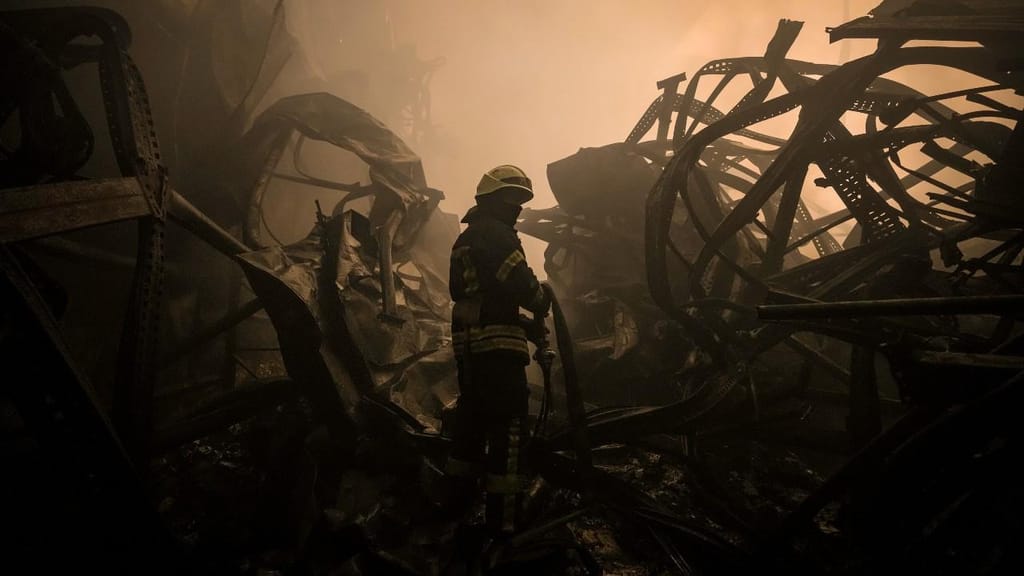 Um bombeiro ucraniano arrasta uma mangueira dentro um armazém de produtos alimentares que foi destruído por um ataque aéreo nos arredores de Kiev, na Ucrânia