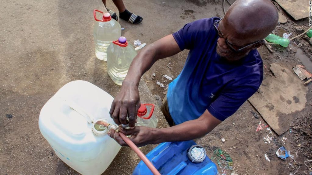 Leonardo Matana, 69 anos, enche um recipiente de plástico com água numa torneira comunitária no município de Kwanobuhle, na África do Sul