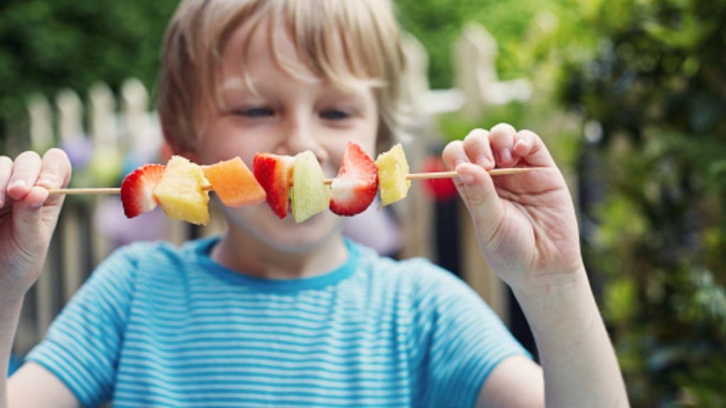 Criança a comer fruta (Getty Images)