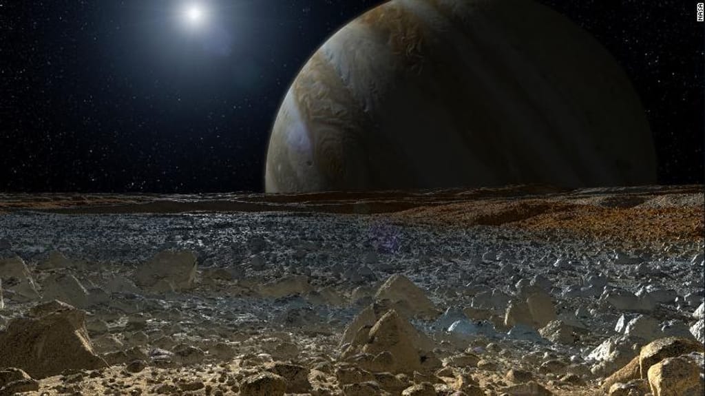 Esta ilustração mostra uma visão simulada da superfície gelada da lua de Júpiter, Europa, com o planeta gigante por trás dela