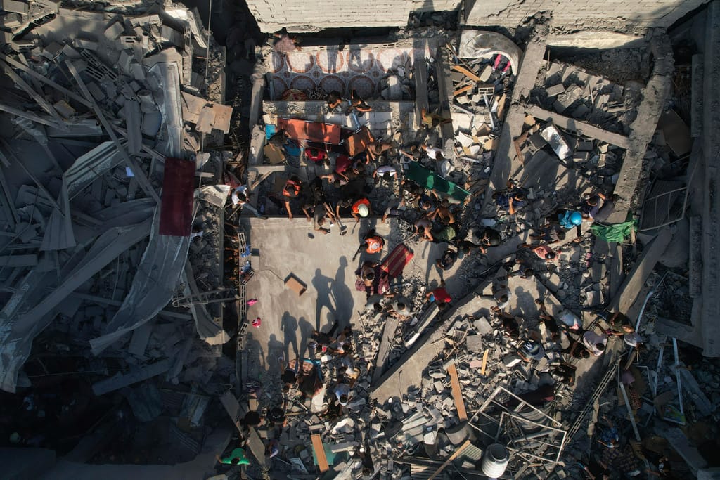 Palestinianos nos escombros de edifícios atingidos por um ataque aéreo israelita no campo de refugiados de Al Shati, a 12 de outubro de 2023. Israel Gaza Foto de Hatem Moussa AP