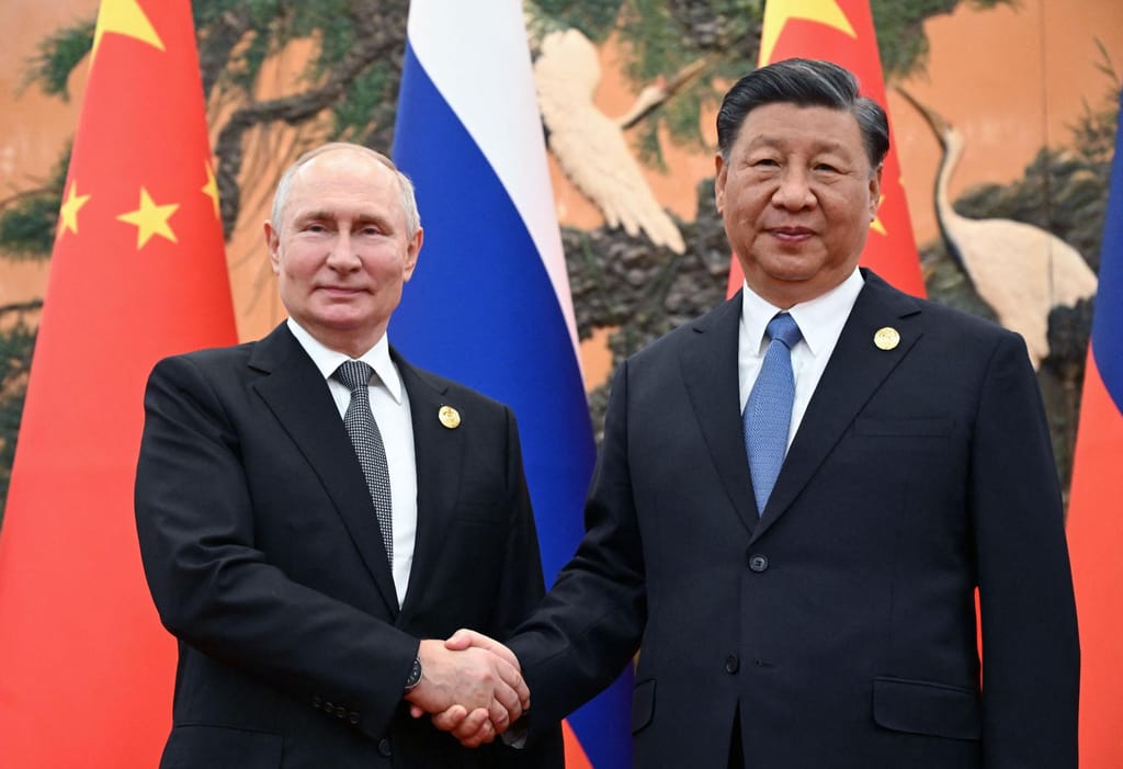 O presidente russo, Vladimir Putin, e o líder chinês, Xi Jinping, apertam as mãos durante uma reunião em Pequim, a 18 de outubro (Sergei Guneyev/AFP/Getty Images)