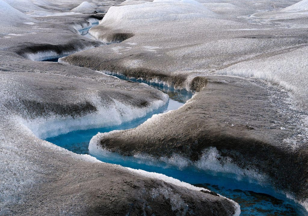 Sedimentos castanhos no gelo derretido perto de Kangerlussuaq, na Gronelândia. O derretimento rápido do gelo está a ter uma série de impactos na paisagem da Gronelândia, incluindo a sedimentação das suas águas.  Martin Zwick/REDA&CO/Universal Images Group/Getty Images