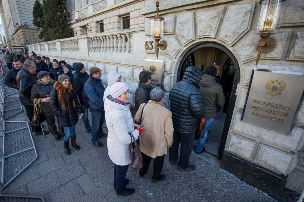 Cidadãos russos na embaixada da Rússia em Berlim, Alemanha, para votar nas eleições presidenciais russas de 2018. Joerg Carstensen/picture-alliance/dpa/AP
