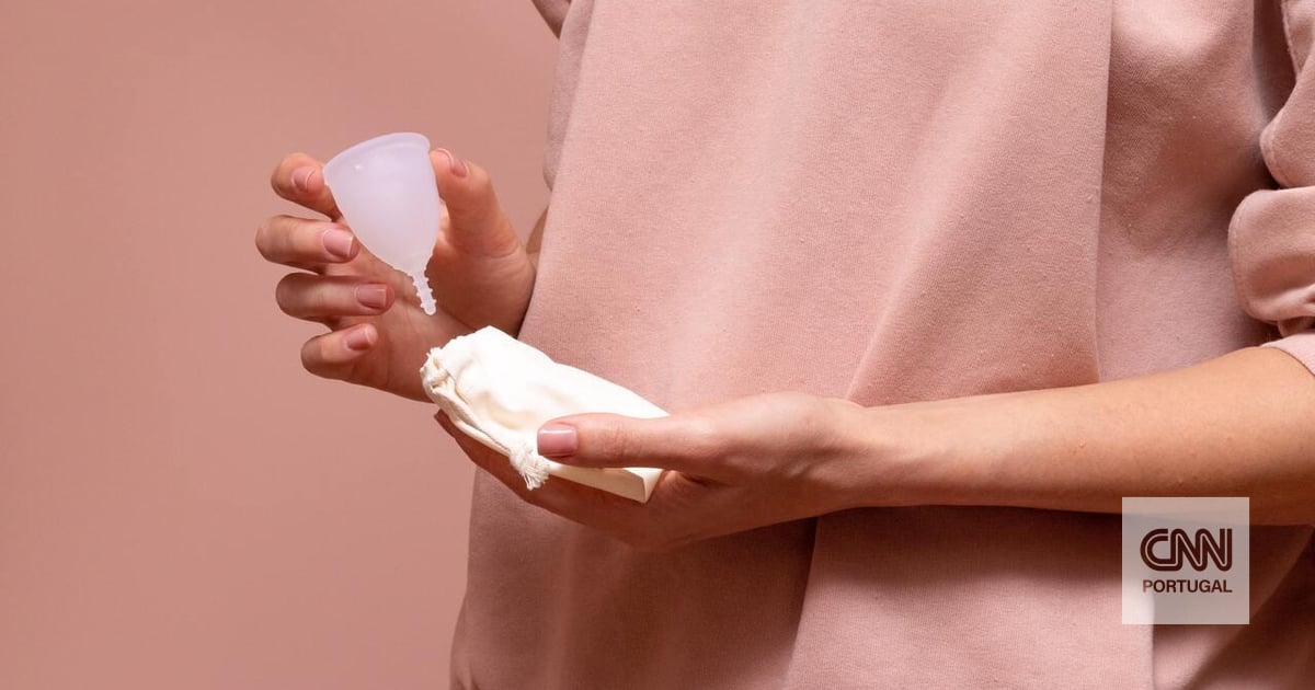 mão de uma mulher segurando o copo menstrual rosa isolado no fundo branco.  mulher moderna alternativa eco ginecológica higiene no período de  menstruação. recipiente para sangue na mão da menina. 5427428 Foto